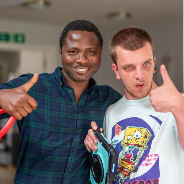 Jake and a support worker smiling and giving a thumbs up